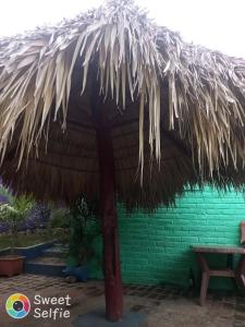a straw umbrella in front of a green building at La Cascada Hostel & Restaurant in Rivas