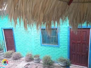 ein blaues Haus mit roten Türen und Topfpflanzen in der Unterkunft La Cascada Hostel & Restaurant in Rivas