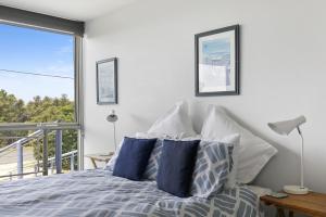 a bedroom with a bed with blue and white pillows at Magnum in Lorne