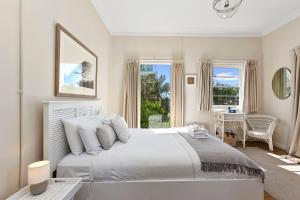 a white bedroom with a large bed and a desk at The White House Prime Location and Oozing Character in Apollo Bay
