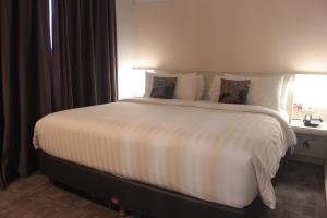 a large white bed in a room with a window at Mercure Jayapura in Jayapura
