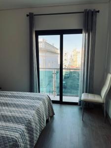 a bedroom with a bed and a chair and a window at Casa Marta e Casa Francisco in Olhão