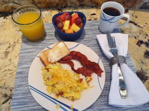 talerz śniadaniowy z jajkami bekonowymi i owocami w obiekcie Fishers Landing Boutique Hotel w mieście Roatán