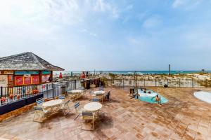 eine Terrasse mit Tischen und Stühlen und das Meer im Hintergrund in der Unterkunft Pelican Beach Resort III in Destin