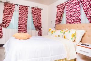 a bedroom with a white bed with red and white curtains at BlueGreens Accommodation in Ndola