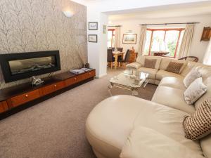 a living room with a white couch and a fireplace at Fir Trees in Windermere