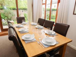 a long wooden table with chairs and glasses on it at Fir Trees in Windermere