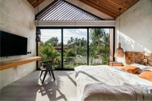 een slaapkamer met een groot bed en een groot raam bij Black Sand Villas in Canggu