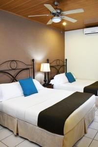 two beds in a hotel room with a ceiling fan at Hotel San Jose, Matagalpa. in Matagalpa