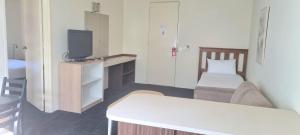 a small room with a bed and a tv at Hotel Cavalier in Wantirna South