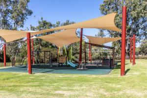 un parque con parque infantil con tejados de bronceado y postes rojos en 4 Pelican Court, Woodlane Mypolonga., en Mannum
