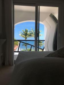 a bedroom with a view of the ocean through a window at Charming Sea Side Ocean Front Condo in Puerto Morelos