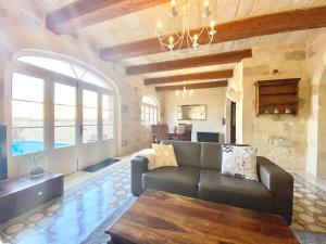 een woonkamer met een bank en een kroonluchter bij Villa Rossa Gozo - 5 bedroom ensuite with pool & jacuzzi in Xewkija
