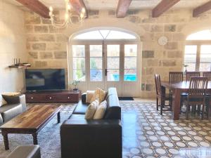 een woonkamer met een bank en een tafel bij Villa Rossa Gozo - 5 bedroom ensuite with pool & jacuzzi in Xewkija