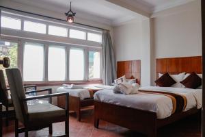 una camera da letto con due letti, una sedia e una finestra di Hotel ThorongLa Thamel a Kathmandu