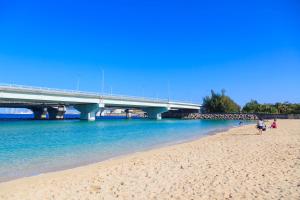 a bridge over a beach with people walking on the sand at Family Room Okinawa in Makishimachi