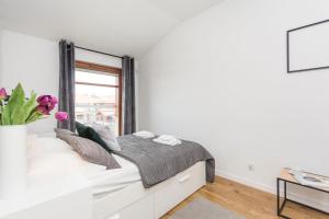 a white bedroom with a bed and a window at Grey Rentyear Apartments in Gdańsk
