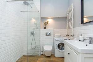 a white bathroom with a sink and a washing machine at Grey Rentyear Apartments in Gdańsk +6 photos