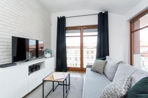 a living room with a couch and a tv at Grey Rentyear Apartments in Gdańsk