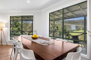 a dining room with a large wooden table and white chairs at Tumbaramba in Wye River
