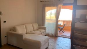 een woonkamer met een witte bank en een balkon bij Casa Sofia vista porto in Olbia