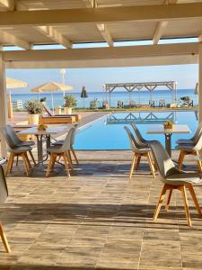 a patio with tables and chairs next to a pool at Nautica Hotel Apartments in Stavromenos