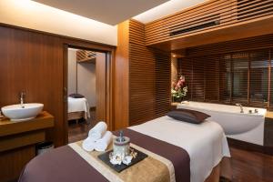 a hotel room with a bed and a tub and a sink at The Landmark Bangkok - SHA Extra Plus in Bangkok