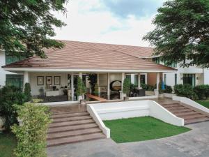 une maison avec une terrasse couverte et une pelouse dans l'établissement The Desiign Hotel - SHA, à Si Maha Phot