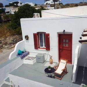une maison blanche avec une porte rouge, une table et des chaises dans l'établissement Venduri House, à Péran Triovasálos