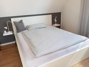 a bedroom with a white bed with white sheets and pillows at Die kleine Auszeit in Gescher