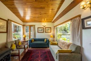 un salon avec un canapé, des chaises et des fenêtres dans l'établissement ama Stays & Trails Ballyhack Cottage,Shimla, à Shimla
