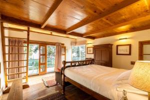 une chambre avec un grand lit dans une pièce avec des plafonds en bois dans l'établissement ama Stays & Trails Ballyhack Cottage,Shimla, à Shimla