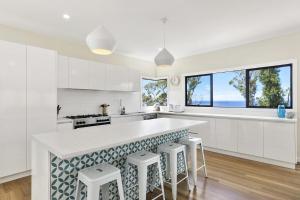 Una cocina con gabinetes blancos y una encimera con taburetes. en Vue Sur La Mer, en Wye River 15 fotos más