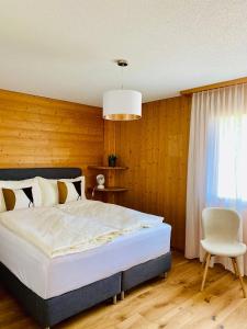 a bedroom with a bed and a chair and a window at Panorama Boutique Apartment with complimentary Spa access at Solbad Hotel in Sigriswil