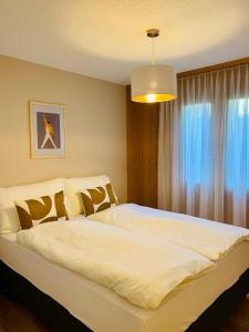een slaapkamer met een groot wit bed en een raam bij Panorama Boutique Apartment with complimentary Spa access at Solbad Hotel in Sigriswil