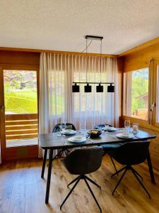 a dining room with a table and chairs and windows at Panorama Boutique Apartment with complimentary Spa access at Solbad Hotel in Sigriswil