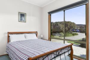 ein Schlafzimmer mit einem Bett und einem großen Fenster in der Unterkunft Bellbird in Aireys Inlet