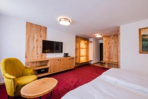a hotel room with a bed and a chair and a television at Villa Conti in Český Krumlov