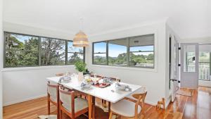 a dining room with a white table and chairs and windows at Tree Scape Retreat in Robertson