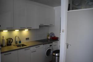 een keuken met witte kasten en een wasmachine bij Duinstraatje 3 in Zoutelande