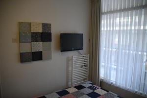 een slaapkamer met een tv en een bed en een raam bij Duinstraatje 3 in Zoutelande