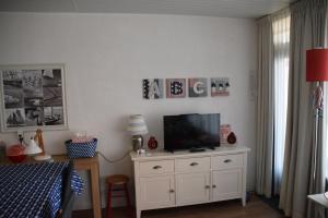een slaapkamer met een televisie op een wit dressoir bij Duinstraatje 3 in Zoutelande