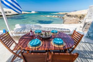 - une table en bois avec des assiettes de nourriture au-dessus de l'océan dans l'établissement Sarakiniko Boat House, à Mandrakia