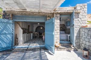 Mandrakia的住宿－Sarakiniko Boat House，一道蓝色的门通向石头房子内的厨房