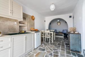 uma cozinha com armários brancos e um piso de pedra em Sarakiniko Boat House em Mandrakia