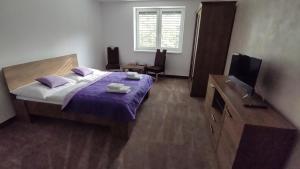 a bedroom with a bed with purple sheets and a television at GÓL CENTRUM RESORT in Sabinov