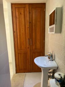 ein Badezimmer mit einem Waschbecken und einer Holztür in der Unterkunft Room in Guest room - Central Area Bedroom With Common Kitchen, living room in Sosúa
