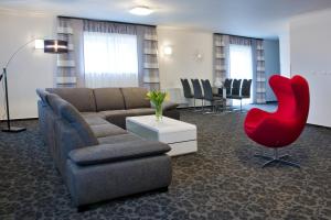 a living room with a couch and a red chair at Parkhotel Plzen Congress Center in Pilsen