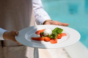 a man holding a plate of food on a tray at La Residenza Capri in Capri