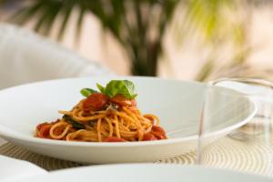 a plate of pasta with basil on a table at La Residenza Capri in Capri